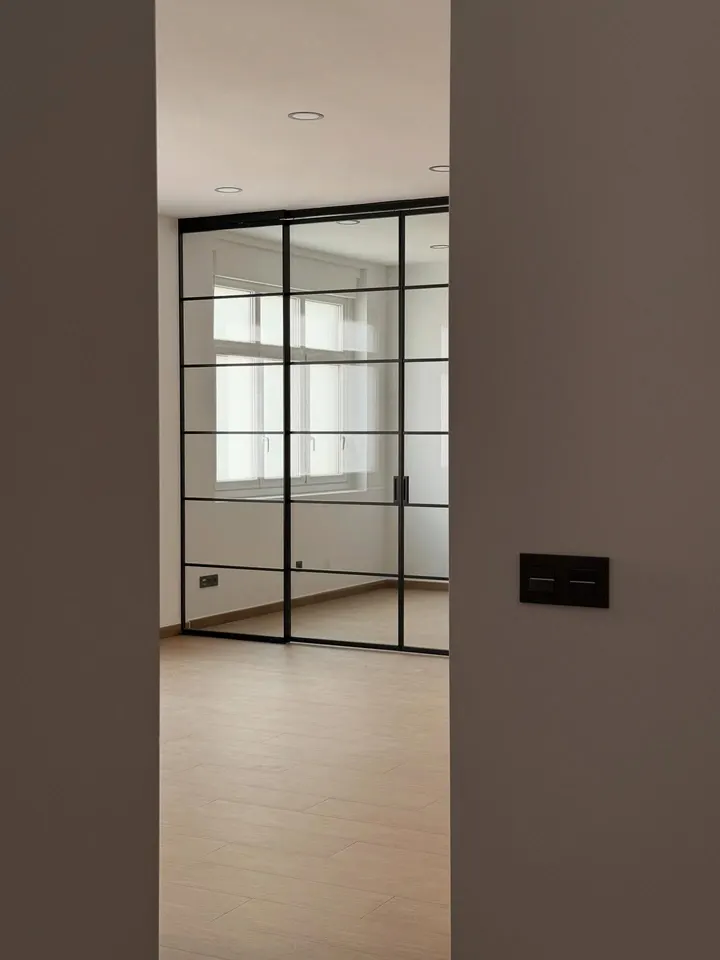 Cerramiento a medida en aluminio negro con sistema de puertas correderas.